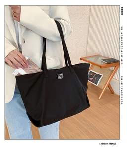 Detail of a black nylon tote bag with fashion logo, ideal for daily commute use