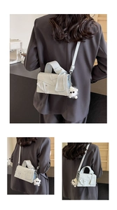 Detail showing asymmetric deconstructed design and plush charm on denim crossbody bag