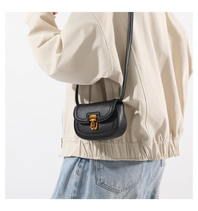 Detail view of a black pebble leather saddle bag with vintage gold clasp on model