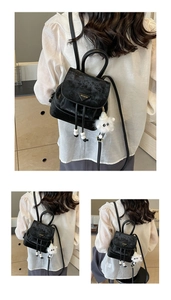 Detailed view of mini black velvet backpack with triangle logo and fluffy monster charm