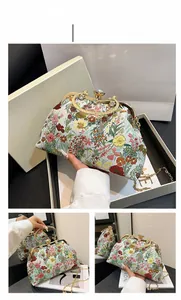 Detail of floral clutch bag with vintage embroidery, gold circular handle and metal chain strap