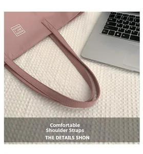 Detail showing the reinforced stitching of pink nylon tote bag straps on office desk