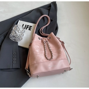 Detail of pink drawstring bucket bag showing matte texture and metal bottom studs