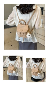 Detail of beige suede mini backpack with drawstring closure and cute plush monster charm