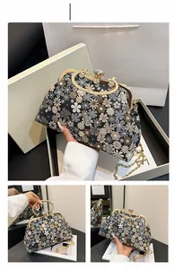 Close-up of elegant floral embroidery, crystal clasp and metal handle on the evening bag