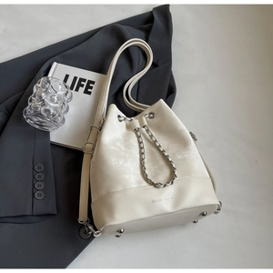 Close-up of cream bucket bag with silk-texture fabric and embossed leather base detail