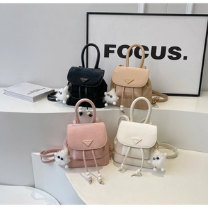 Detail view of four mini backpacks in black, apricot, pink, and white with plush charms
