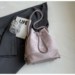 Detail of light pink bucket bag with drawstring chain, velvet and leather materials