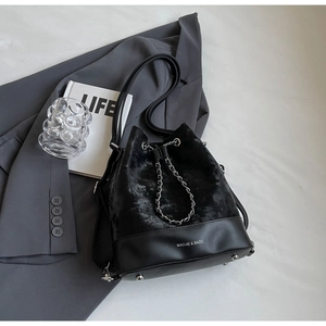 Detail of black drawstring bucket bag with textured fabric, matte leather, and silver chain