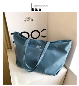 Detail of blue waterproof nylon tote bag featuring a square logo patch on the front