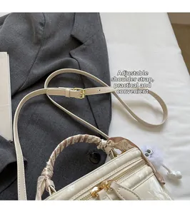 Detail van de gebroken witte crossbodytas met verstelbare riem en decoratieve zijden sjaal