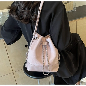 Detail view of pink matte leather drawstring bucket bag with elegant metal chain straps