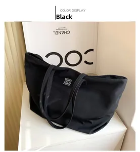 Close-up of a large black nylon tote bag featuring a minimalist white square brand label