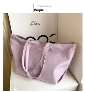 Detail of a purple nylon tote bag featuring a white square woven label and smooth texture
