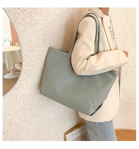 Detail view of large grey-green tote bag showing its matte texture and shoulder strap
