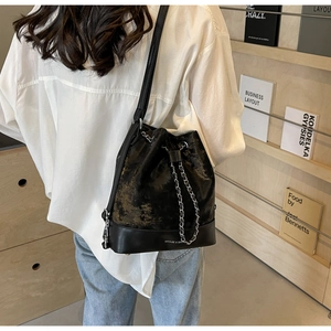Detailed view of black drawstring bucket bag with silver chain and white logo print