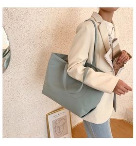 Minimalist light blue waterproof nylon tote bag shown on shoulder for daily commuting