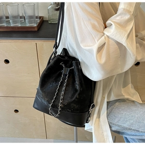 Detail of black velvet bucket bag with leather base and silver metal chain drawstring