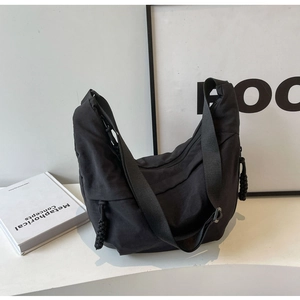 Detail view of the black nylon crescent bag with wide strap and woven zipper puller