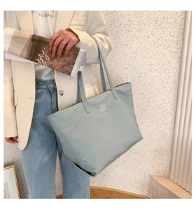 Mint green nylon tote bag detail with modern fashion woven label shown on model