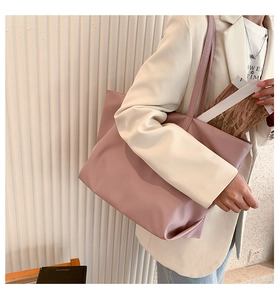 Spacious dusty pink nylon tote bag styled on shoulder for professional daily commuting