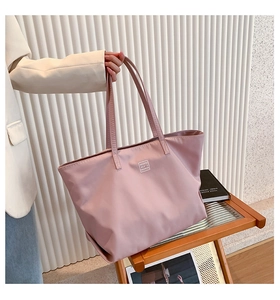 Close-up of pink nylon tote bag with MODIFEI logo and reinforced stitching detail