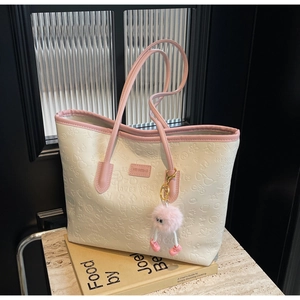 Detail view of cream tote bag with pink straps and embossed heart patterns