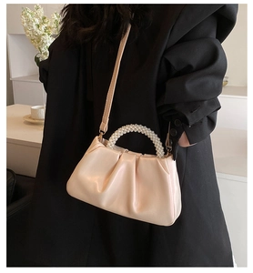 Detail showing the pearl beaded handle and pleated leather texture of a cream cloud bag