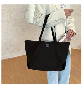 Detail of the MODIFE BAG'S FASHION logo on a large black nylon commuter tote bag