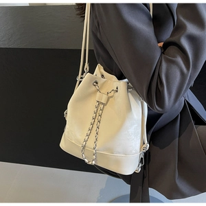Close-up of white drawstring bucket bag with silver metal chain on a model wearing black