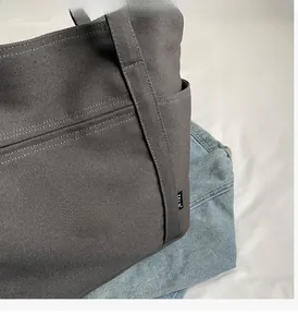 Detail of dark gray heavy canvas tote bag with woven brand label and durable texture