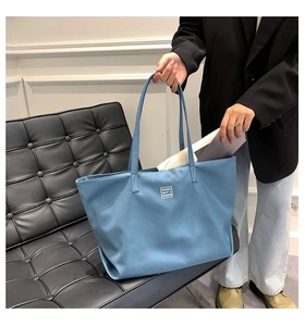 Detail of blue nylon tote bag showing spacious interior and woven logo label