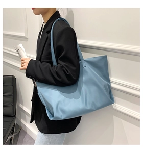 Sky blue nylon tote bag worn by a model in a black suit for urban casual commute