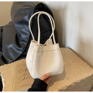 Gros plan du sac seau blanc crème avec une texture plissée douce sur une pierre