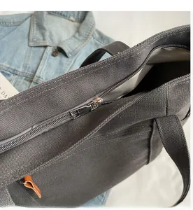 Close-up of smooth silver metal zipper and dark gray canvas texture on tote bag