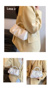 Detail of white pleated cloud bag with pearl handle and satin finish texture