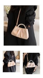 Detail of elegant beige dumpling bag featuring a pearl handle and ruched texture