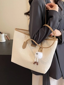 Minimalist cream and brown tote bag with embossed textures and plush doll pendant