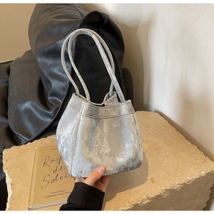 Gros plan détaillé d'un sac seau argenté métallisé sur un fond industriel épuré