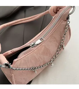 Close-up of smooth metal zipper and textured pink faux leather on the crossbody underarm bag