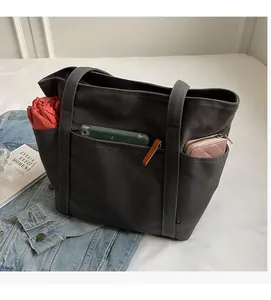 Close-up of dark grey canvas tote bag with multi-pocket storage for phone and umbrella