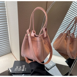 Vue détaillée du sac seau rose clair avec texture daim et sangle à rivets métalliques