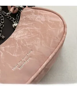 Close-up of pink ruched leather bag featuring silver chain, heart and star charms