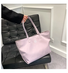 Detail shot of lavender purple nylon tote bag with black straps and logo on a black chair
