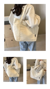 Detail view of a large cream canvas tote bag with side pockets and a black brand label