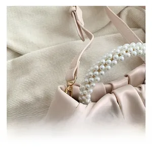 Detail of the pearl woven handle and light gold metal hook on the pleated cloud bag