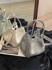Sac à main seau minimaliste beige et argenté avec fermeture plissée et finitions dorées