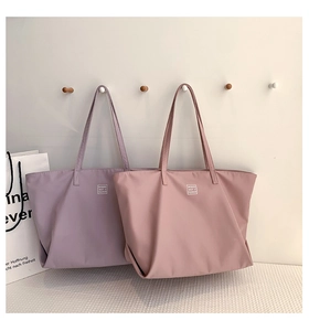 Detail view of purple and lotus pink nylon tote bags hanging in a minimalist setting
