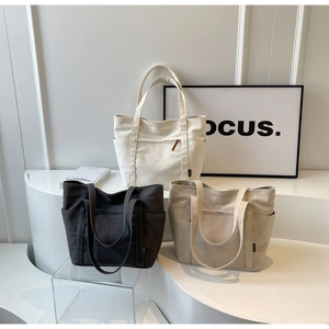 Detail of canvas tote bags in white, black and beige with functional front zipper pockets