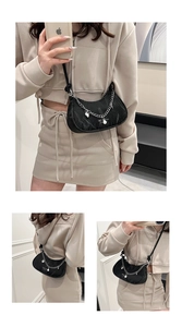 Detail of black crescent shoulder bag featuring silver chain and pearl charms detail